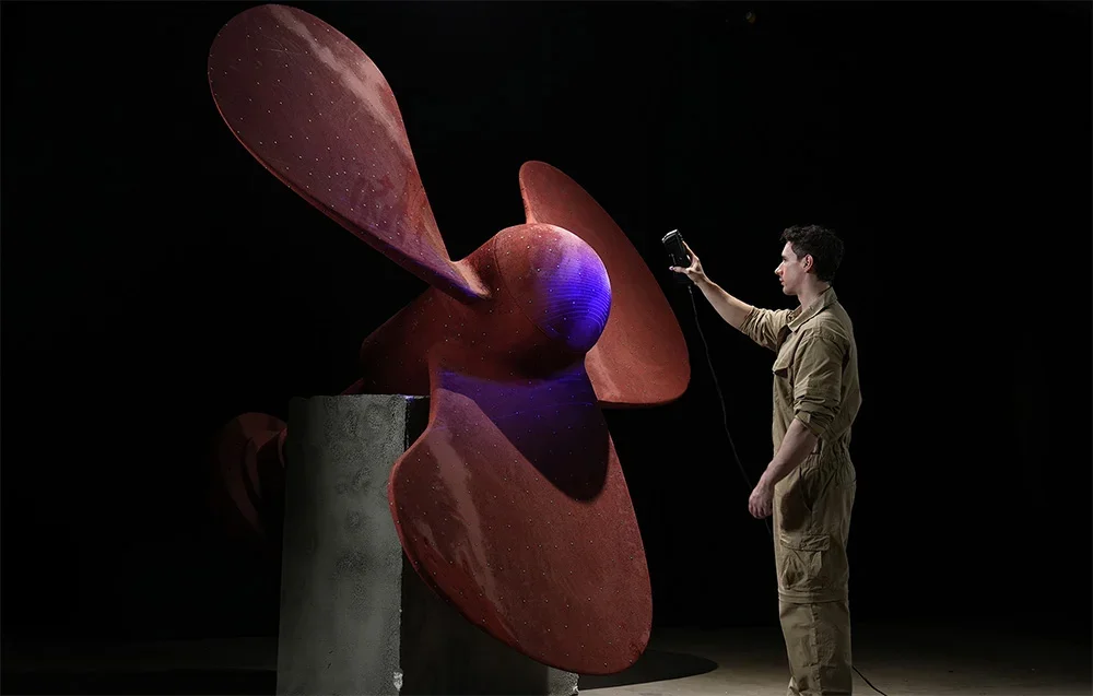 Technikas skenuoja didelį raudoną laivo sraigtą su 3D scanner